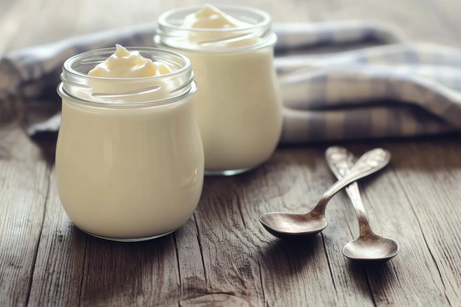 cream in glass jars with spoons on a wooden table