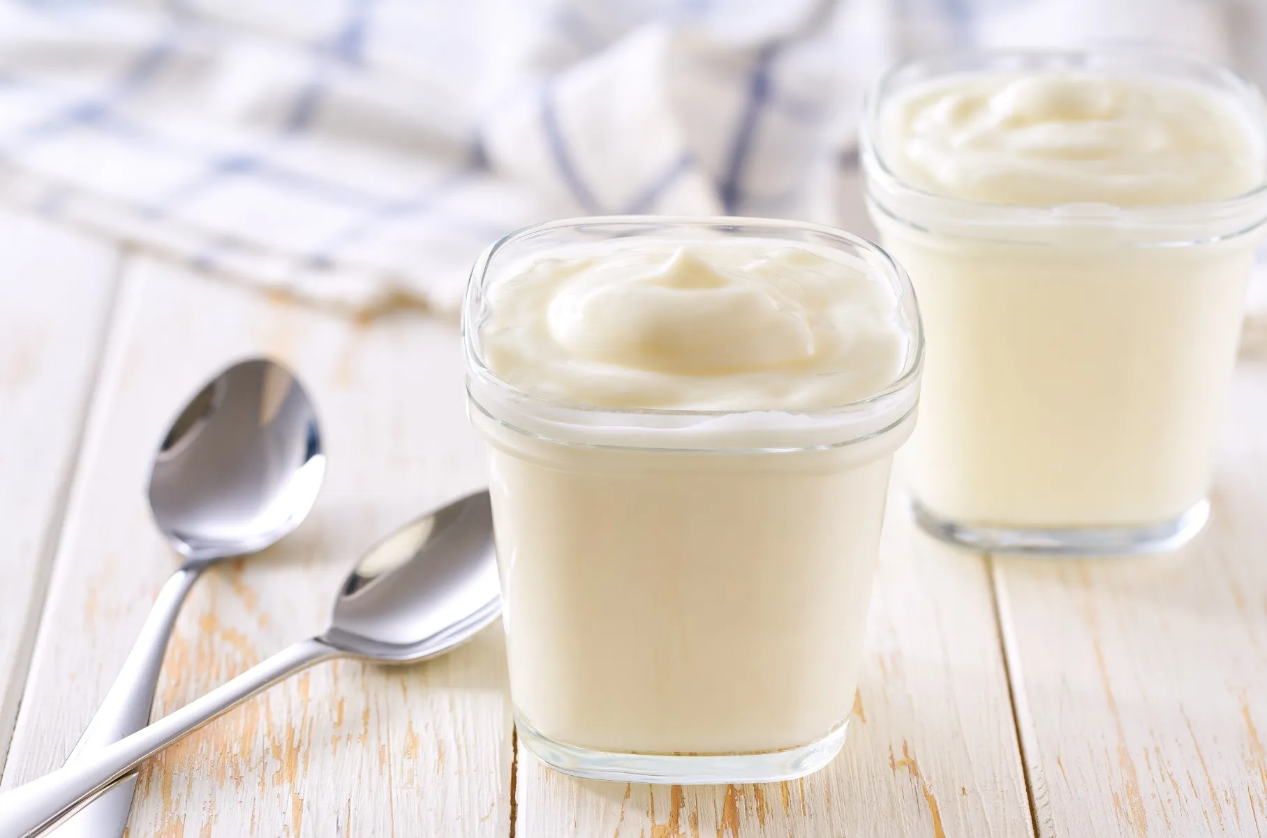 cream in glass jars with spoons on a wooden table
